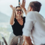 Businesswoman giving a high five to male colleague in meeting. Business professionals high five during a meeting in boardroom.